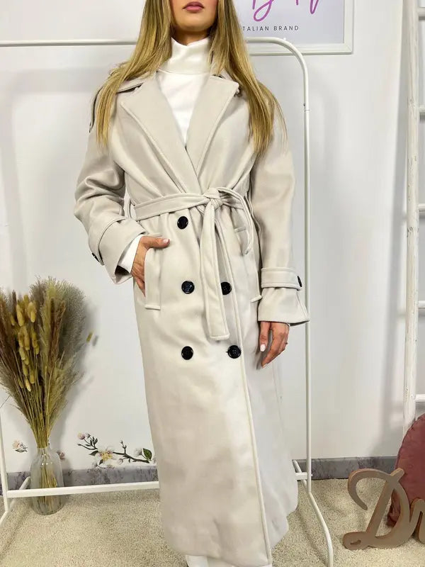 This double-breasted coat features button closure, a built-in belt, and practical pockets, showcasing refined elegance and versatile practicality