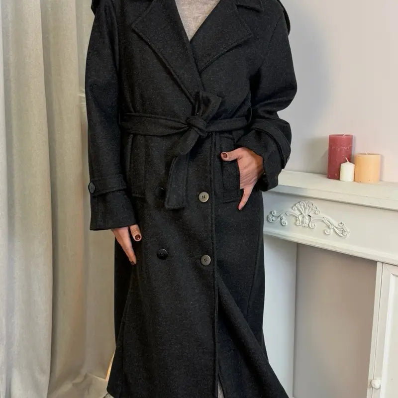 This double-breasted coat features button closure, a built-in belt, and practical pockets, showcasing refined elegance and versatile practicality