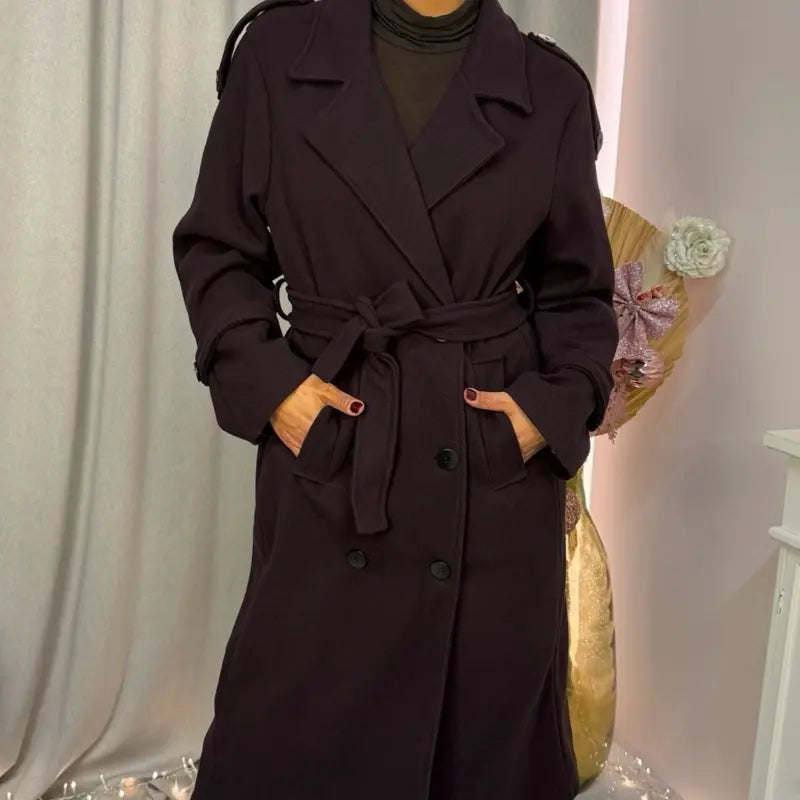 This double-breasted coat features button closure, a built-in belt, and practical pockets, showcasing refined elegance and versatile practicality