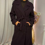 This double-breasted coat features button closure, a built-in belt, and practical pockets, showcasing refined elegance and versatile practicality
