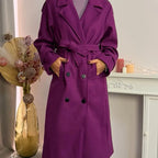 This double-breasted coat features button closure, a built-in belt, and practical pockets, showcasing refined elegance and versatile practicality
