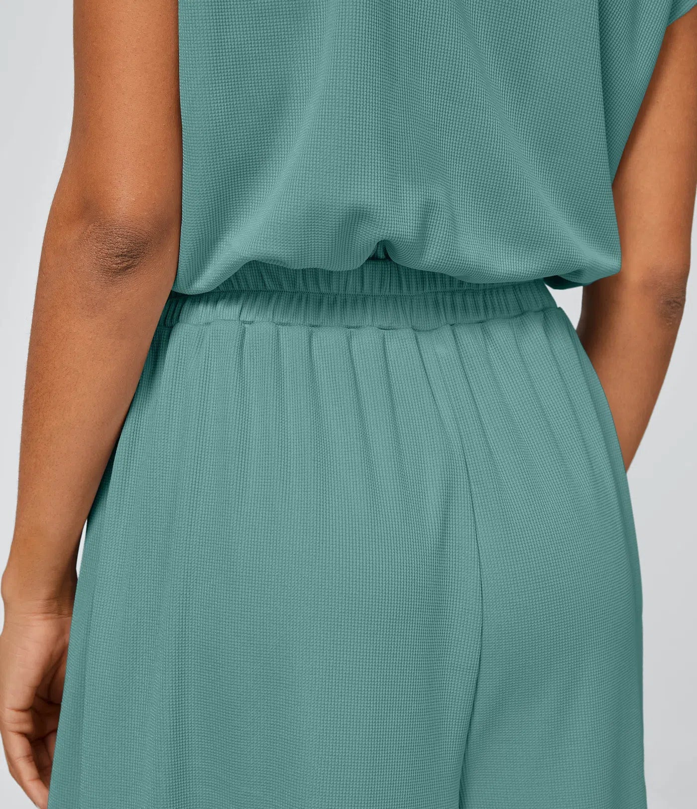 Casual jumpsuit with V-neck, wide legs, pleated, short sleeves, and flowy waffle pattern.