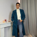 This double-breasted coat features button closure, a built-in belt, and practical pockets, showcasing refined elegance and versatile practicality