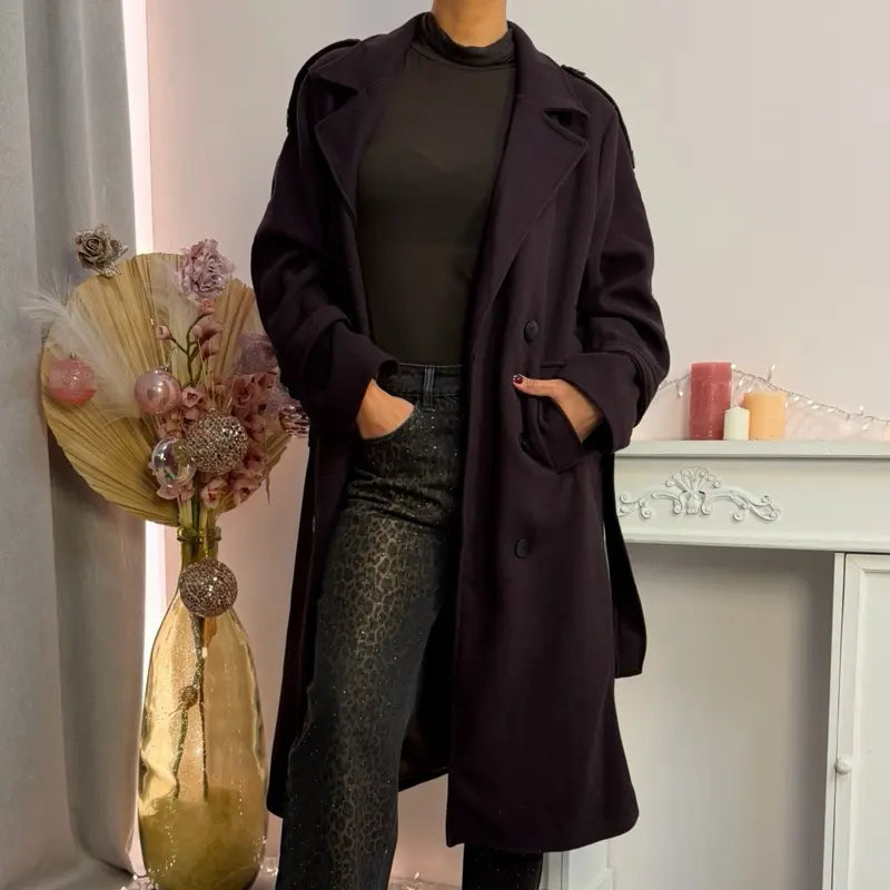 This double-breasted coat features button closure, a built-in belt, and practical pockets, showcasing refined elegance and versatile practicality