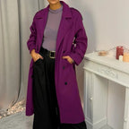 This double-breasted coat features button closure, a built-in belt, and practical pockets, showcasing refined elegance and versatile practicality